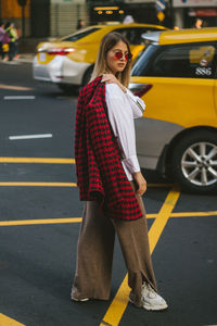 Side view portrait of young female model standing on city street