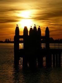 Silhouette pier over sea against sky during sunset