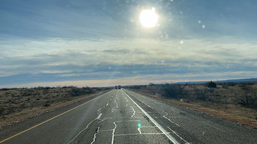 Road passing through landscape against cloudy sky