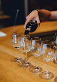 Midsection of person pouring wine in glass on table