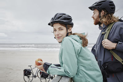 Germany, schleswig-holstein, st peter-ording, couple on a bicycle trip having a break on jetty at the beach