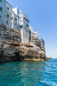 Sea by buildings against clear blue sky