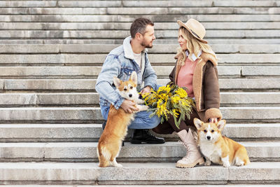 A couple in love on a date. a blonde in a hat and a man look at each other. walking with corgi dogs