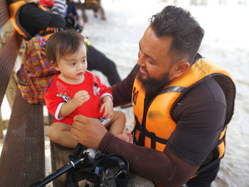 Father looking at cute daughter against sea