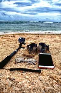 Close-up of camera on beach against sky