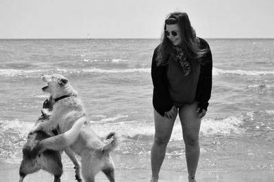 Woman standing by dogs at beach