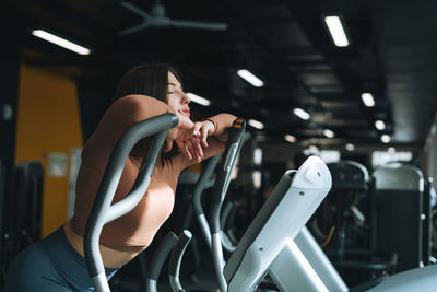 Young tired woman training for cardio equipment at fitness gym