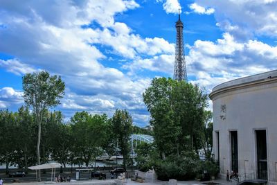 Trees and buildings against cloudy sky