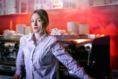 Portrait of young woman standing at cafe