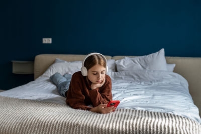 Young woman sitting on bed at home