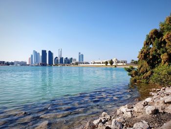 Sea by buildings against clear sky