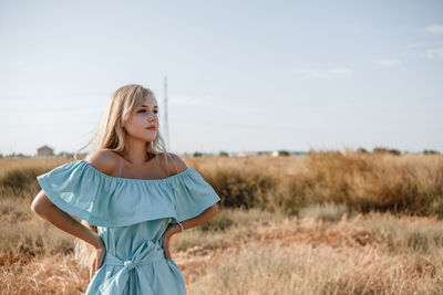 Teenage girl wearing dress standing on land against sky