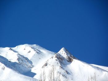 Low angle view of snow against clear blue sky