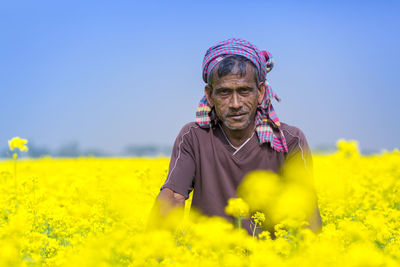 Portrait of man with yellow flowers in field