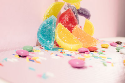 Colorful jelly and skittles candys against pastel pink and shiny background. creative concept