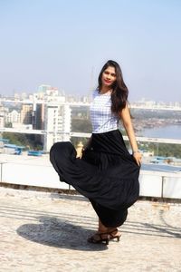 Portrait of beautiful woman in city against sky