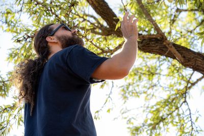 Low angle view of man standing against tree