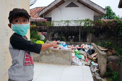Boy wearing pollution mask while standing on sidewalk