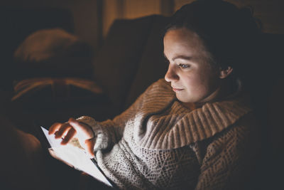 Woman using tablet computer while relaxing on sofa at home