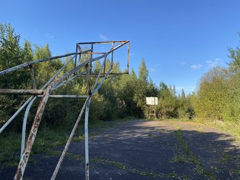 Empty road amidst trees against clear blue sky