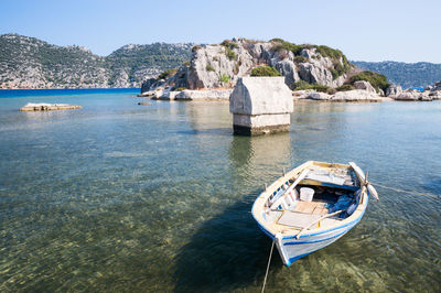 Boat moored on sea against mountain