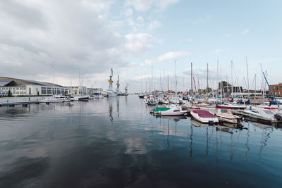 Boats moored at harbor against sky