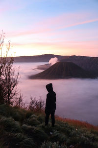  man standing on mountain against sky during sunset