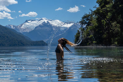 Rear view of woman with arms raised in lake