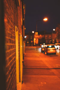 Illuminated street light by building in city at night