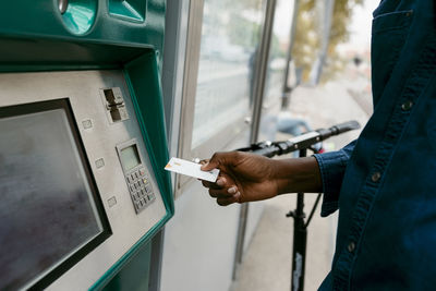 Male commuter inserting credit card while buying ticket at machine