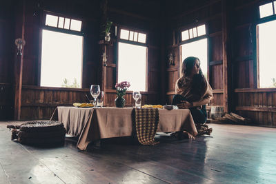 Young woman looking away while sitting at table