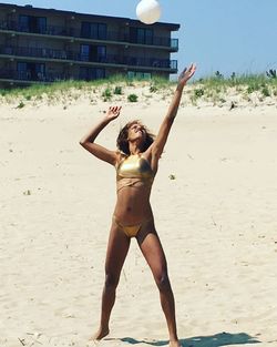 Full length of shirtless young woman standing on beach