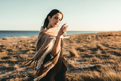 Side view of young woman standing by sea against sky