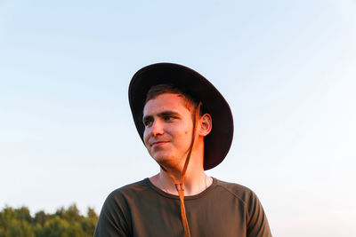 Young man smiling farmer in cowboy hat at agricultural field. profile portrait of man standing 