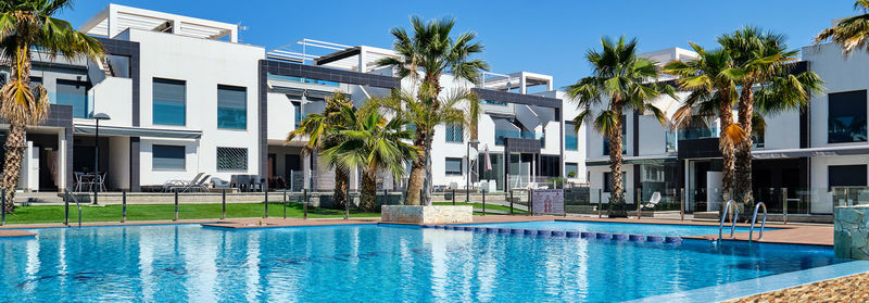 Swimming pool by building against blue sky