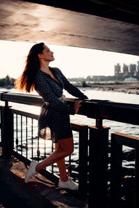 A woman is standing under a bridge