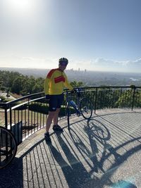 Man riding bicycle on railing against sky