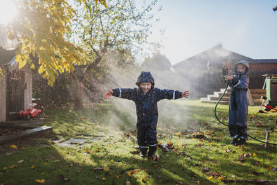 Children playing in garden with garden hose