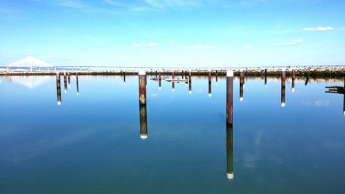 Wooden posts in sea against sky