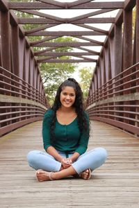 Portrait of young woman sitting on bridge