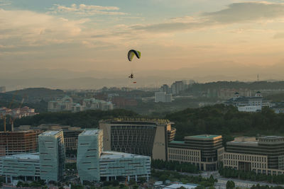 Hot air balloons flying over city against sky