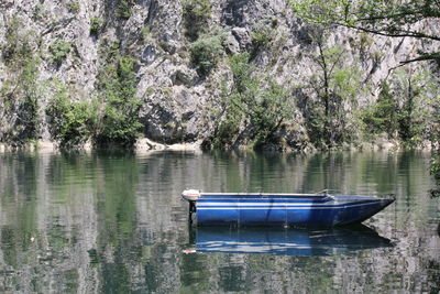 Blue boat moored in river against rocky mountains