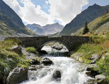 Bridge over river amidst mountains against sky