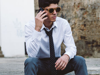 Man in sunglasses talking on mobile phone while sitting outdoors