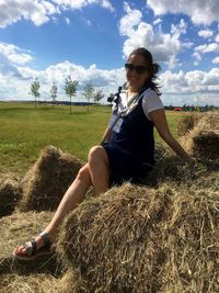 Full length of woman sitting on field against sky