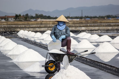 Full length of man standing by wheel barrow in salt flat during winter