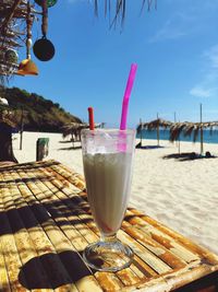 Close-up of drink on glass at beach against sky