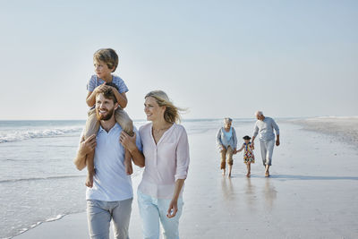 Happy extended family strolling on the beach