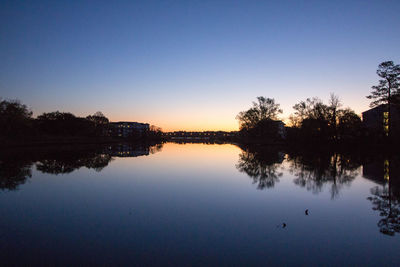 Reflection of trees in calm lake at sunset