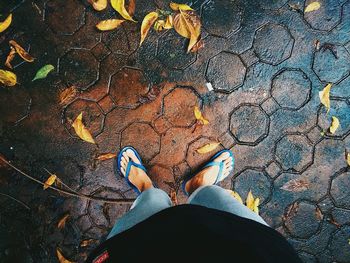 Low section of man standing on wet footpath